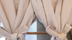 Una ventana con marco de madera y cortina atada con un nudo.