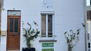A white building with a wooden door, two windows, and a signboard. - Suite Savane with Jacuzzi 15min Disney (Nanteuil-lès-Meaux)