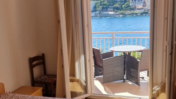 A bedroom with a bed, a chair, and a balcony with a table and chairs.