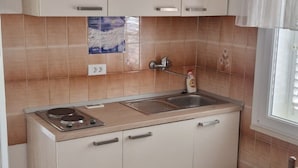 A compact kitchen with a sink, stove, and cabinet doors.