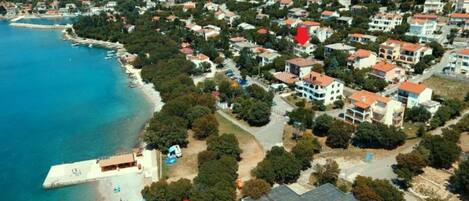 An aerial view of a coastal town with houses, a beach, and a pier.