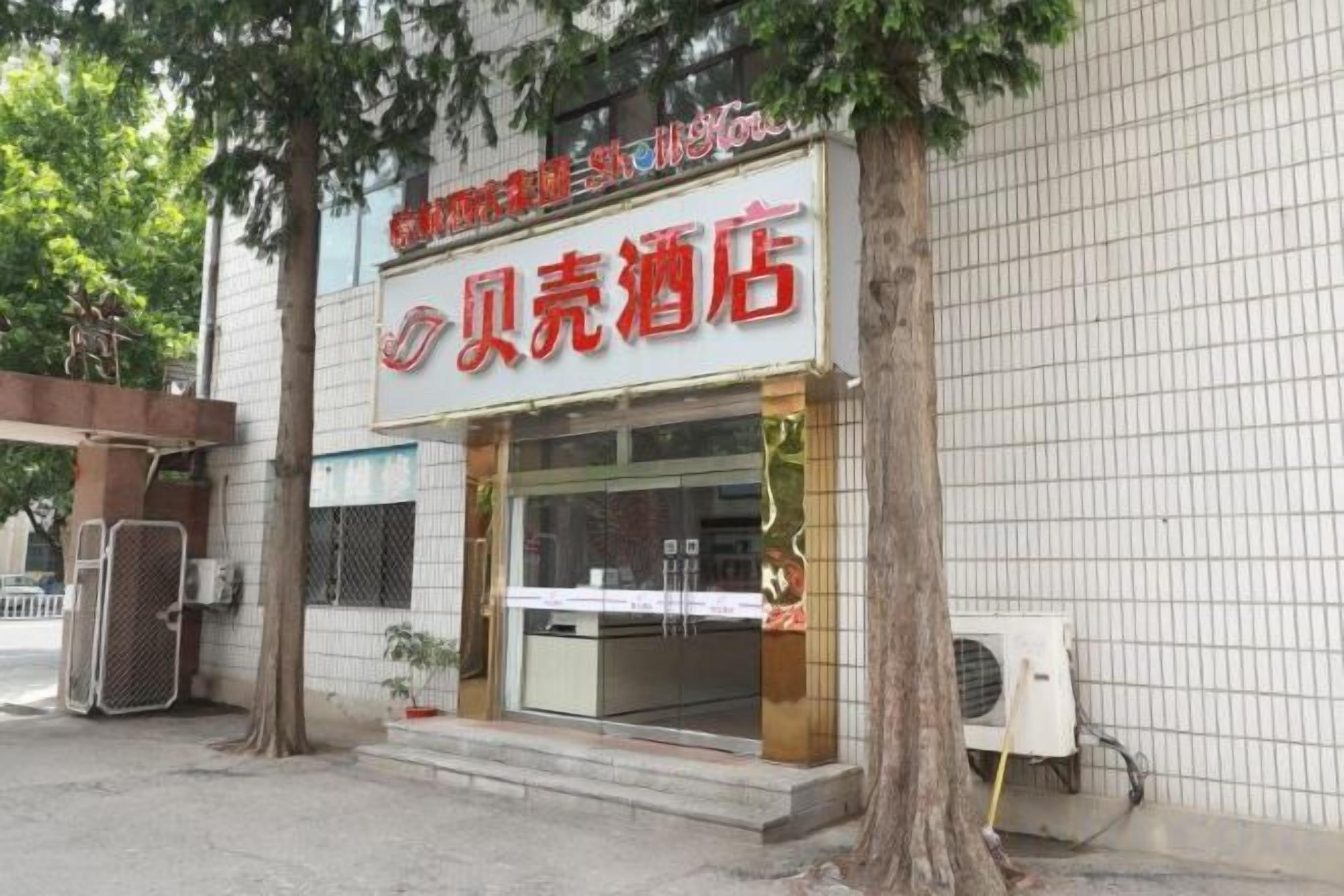 A hotel with a signboard, a glass entrance, and a tiled wall.