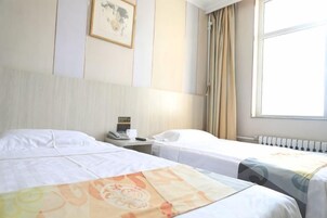 Habitación de hotel con dos camas, una mesita de noche, un teléfono y una ventana con cortinas.