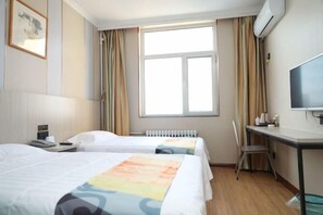 A hotel room with two beds, a desk, a chair, a TV, and a window with curtains.