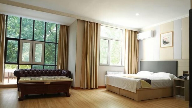A bedroom with a bed, a sofa, large windows, and a view of greenery. - Shell Hotel (Zhaoyuan Wenquan Road) (Zhaoyuan)