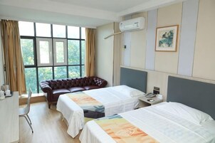 Habitación de hotel con dos camas, un escritorio, una silla, una ventana con cortinas y un cuadro en la pared.
