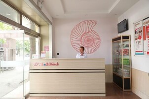 Un mostrador de recepción de hotel con una gran obra de arte en espiral en la pared, una zona de recepción y una vitrina con objetos.