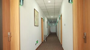 A hotel hallway with wooden doors, framed pictures on the walls, and emergency exit signs. - Shell Hotel (Zhaoyuan Wenquan Road) (Zhaoyuan)
