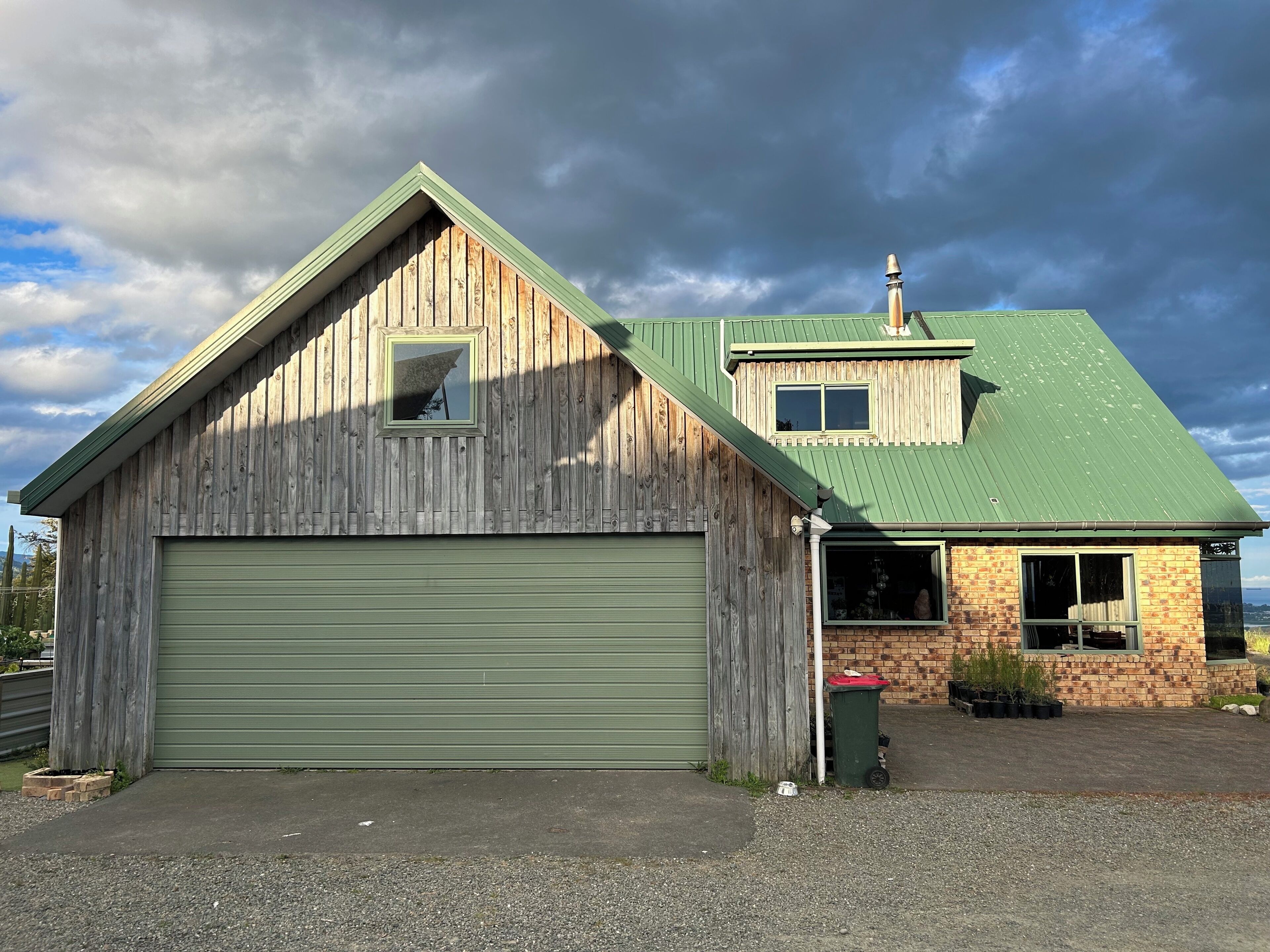 A two-story building with a green garage door and a small attached brick structure.