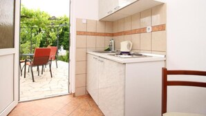 Una cocina compacta con horno integrado, cafetera y lavamanos.