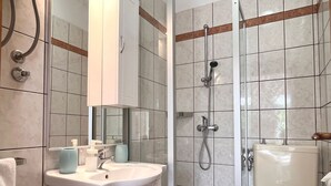 Un baño moderno con lavamanos, espejo y ducha.