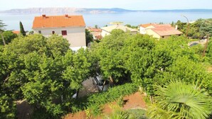 A coastal residential area with houses, lush greenery, and a view of the sea.