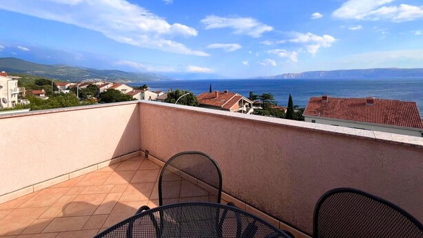 A balcony with a view of the sea and distant hills.