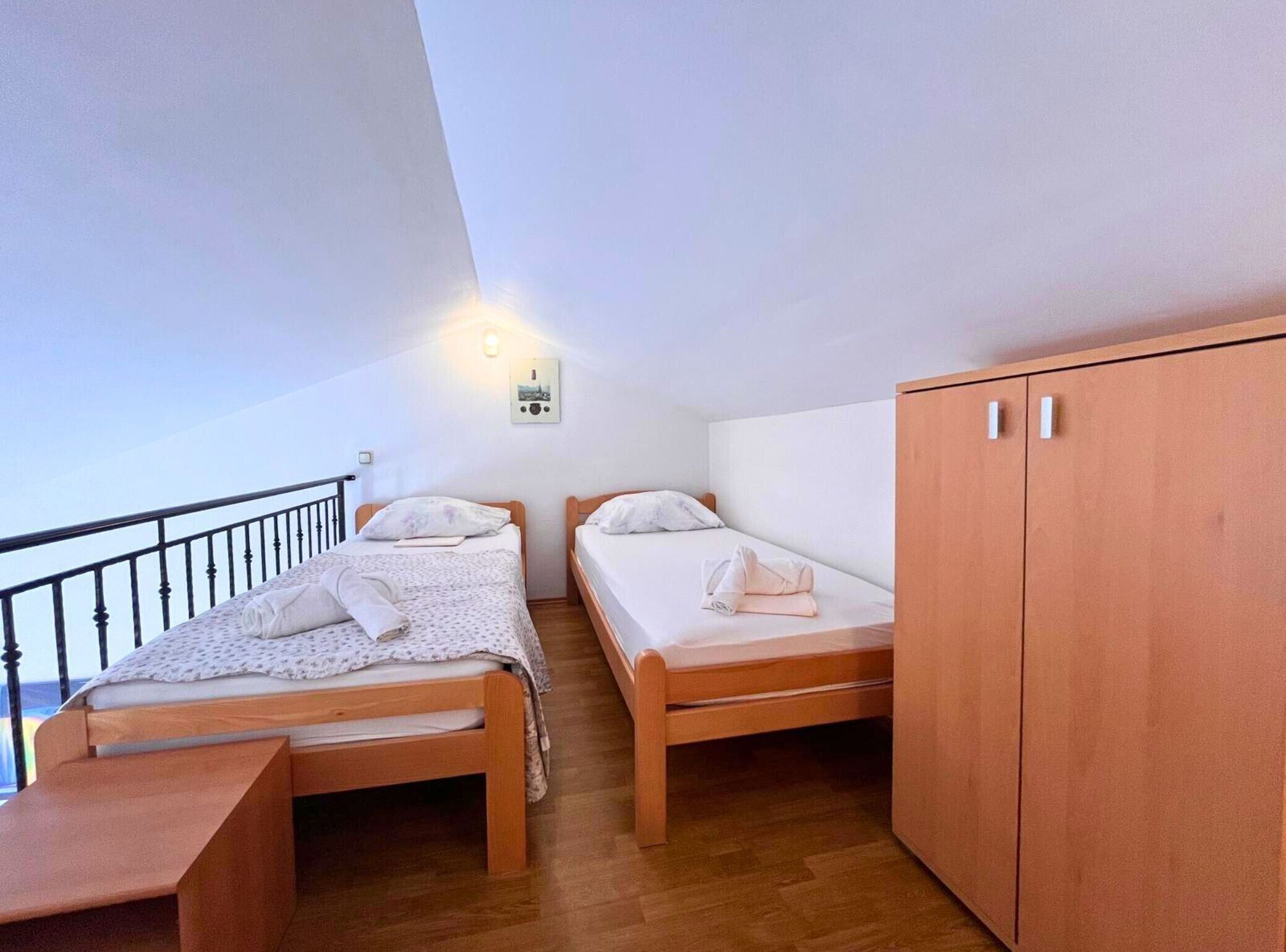 Ein Zimmer mit zwei Holzbett, einem Holzschrank und einem kleinen Tisch.
