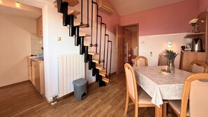 A compact kitchen with a built-in stove, a dining area with a table and chairs, and a staircase with a modern design.