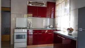 A modern kitchen with red cabinetry, a white stove, and a sink.