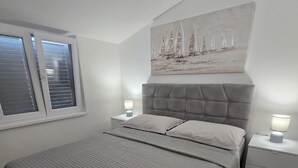 Una camera da letto con un letto grande, due comodini, una finestra con tende e un quadro appeso al muro.