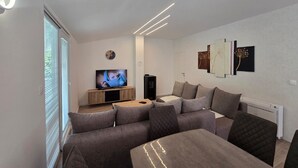 Un soggiorno moderno con un divano, una TV e opere d'arte alle pareti.
