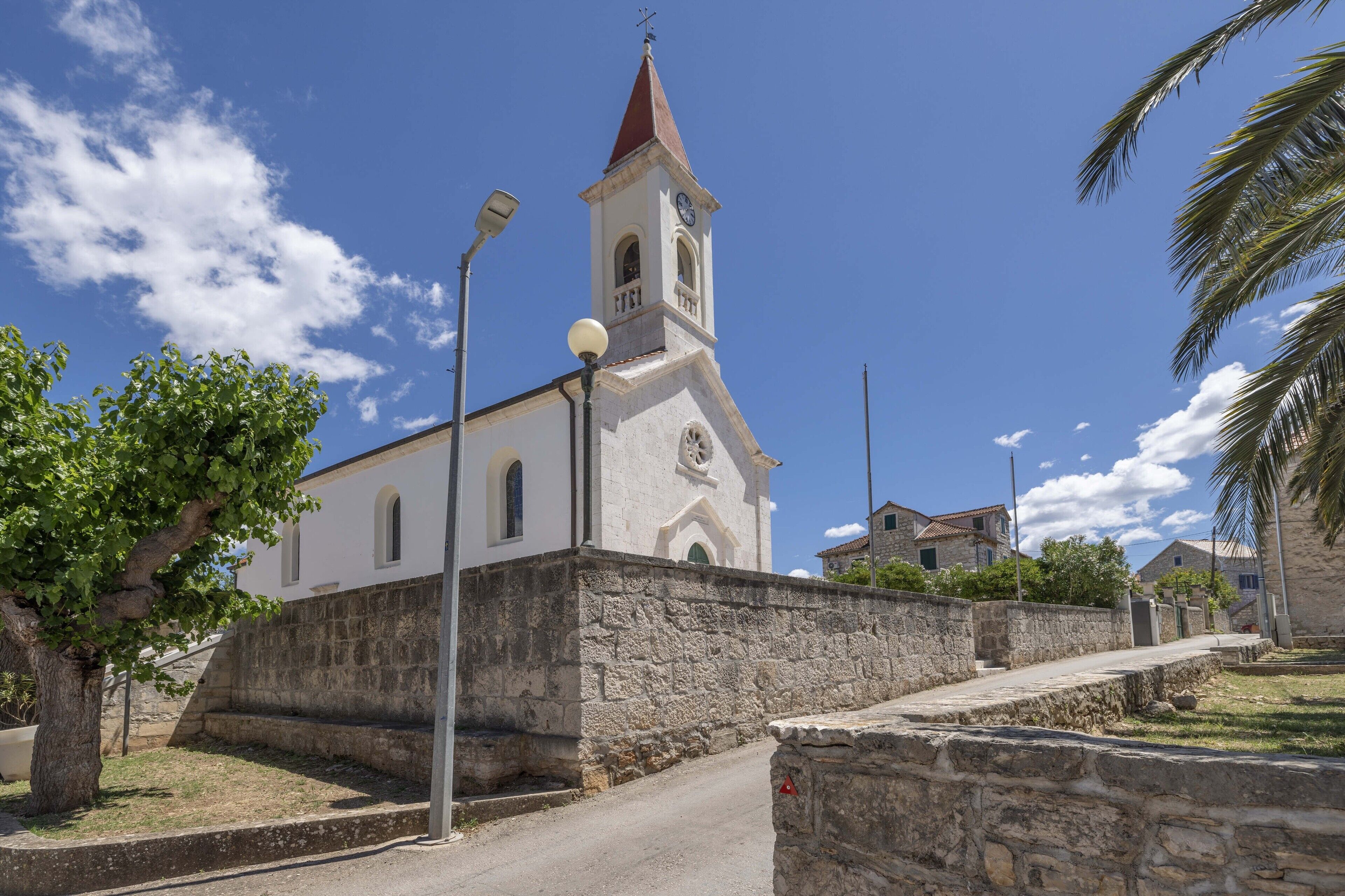 A church with a bell tower, stone walls, and a clear blue sky.