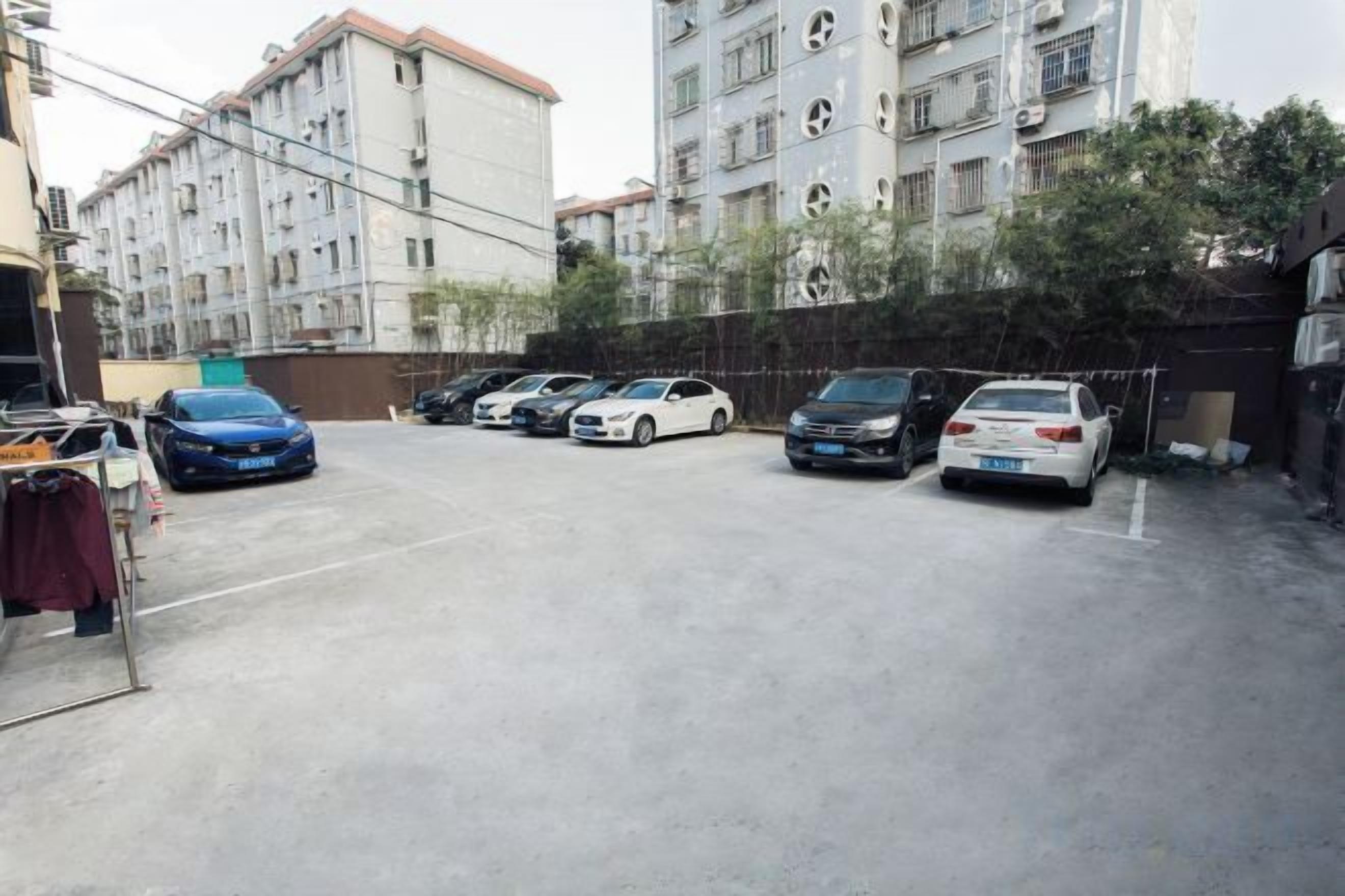 A parking lot with several cars, surrounded by multi-story residential buildings.