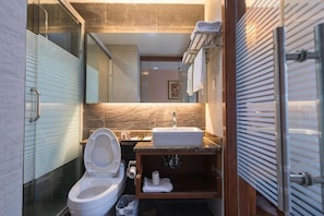 A modern bathroom with a glass shower enclosure, a toilet, a sink, and a mirror. - A&A Chain Hotel (Chuansha East Huaxia Road Subway Station) (Shanghai)