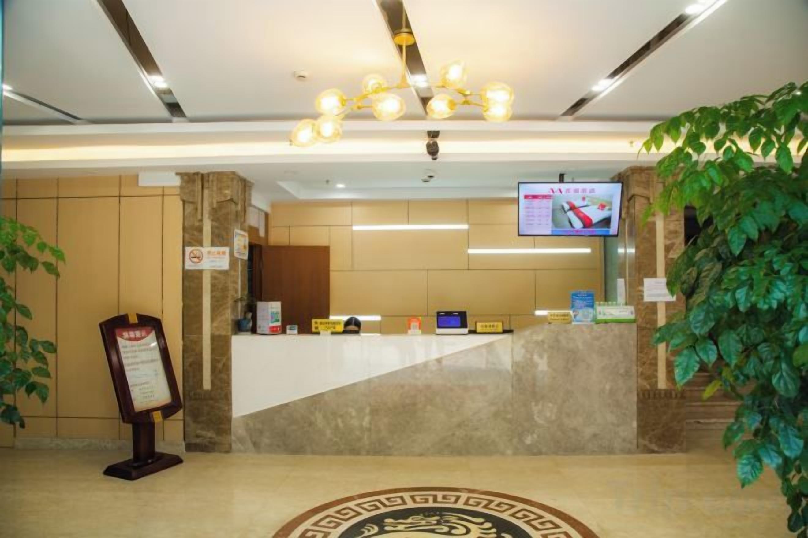 A reception area with a marble counter, a television screen, and a potted plant.