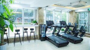 A gym with treadmills, exercise bikes, and a reception area with chairs and a counter. - A&A Chain Hotel (Chuansha East Huaxia Road Subway Station) (Shanghai)