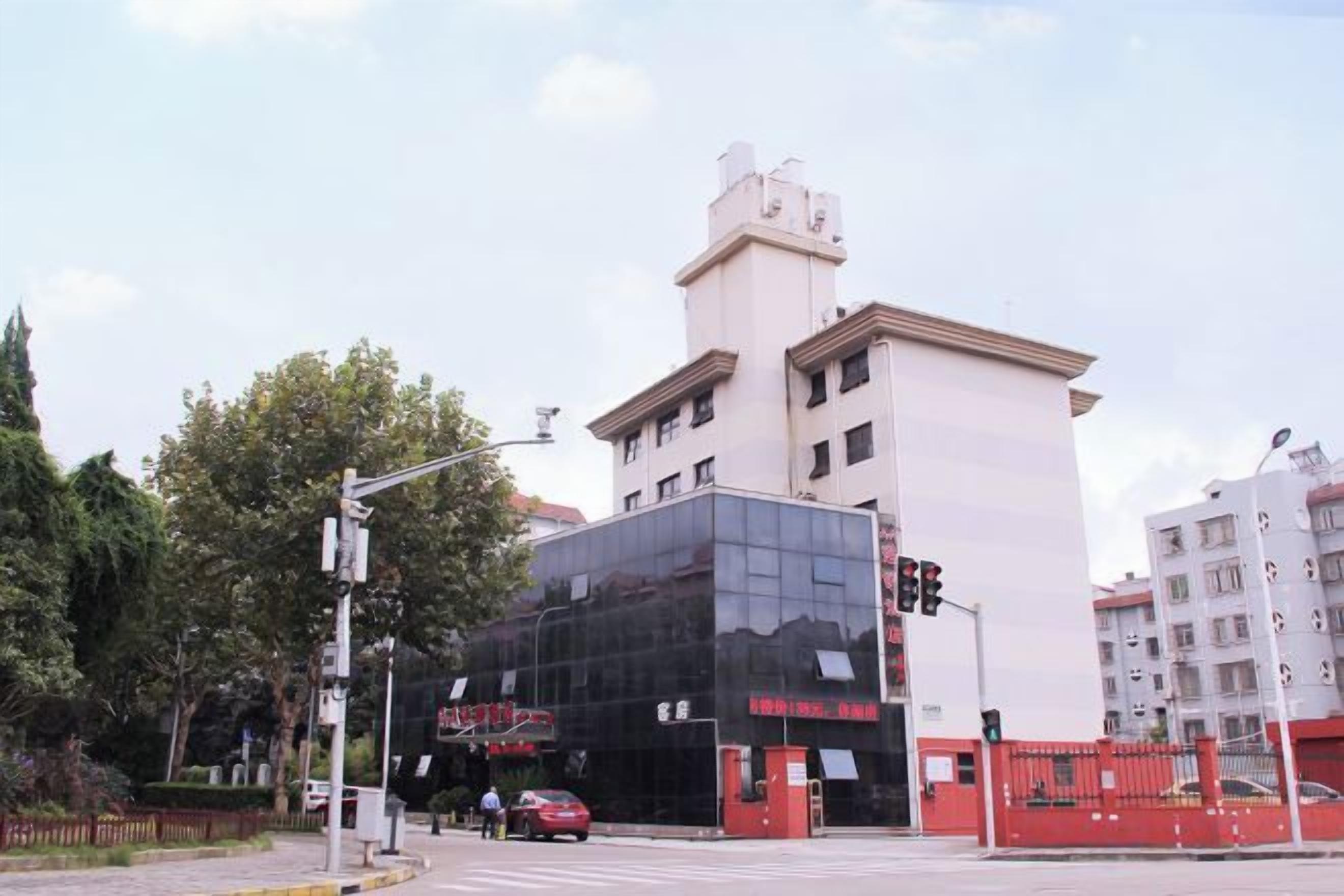 Un edificio moderno con fachada de vidrio, una entrada visible y una reja roja.