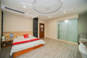 A hotel room with a bed, bedside table, and a glass partition wall.