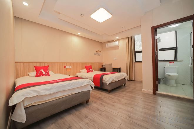 A hotel room with two beds, a desk, and a bathroom.