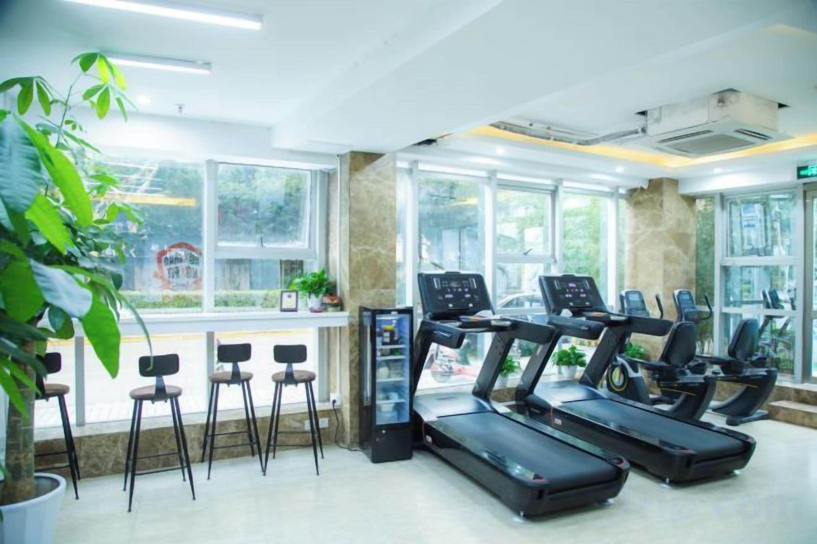 A gym with treadmills, a digital kiosk, and a seating area with chairs.