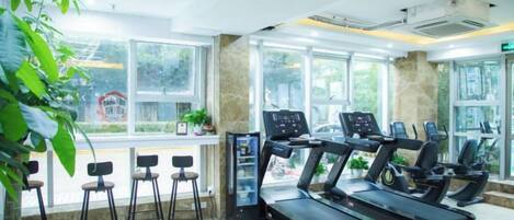 A gym with treadmills, a digital kiosk, and a seating area with chairs.
