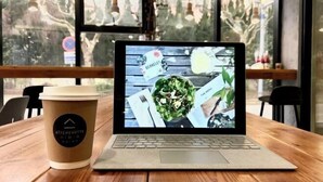 A laptop on a wooden table with a coffee cup beside it. - A&A Chain Hotel (Chuansha East Huaxia Road Subway Station) (Shanghai)