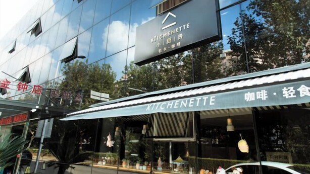 A modern building with a reflective glass facade and a sign for 'KITCHENETTE' restaurant. - A&A Chain Hotel (Chuansha East Huaxia Road Subway Station) (Shanghai)