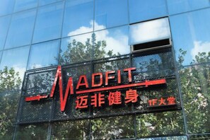 A building with a reflective glass facade and a sign with the text 'MADFIT' and Chinese characters. - A&A Chain Hotel (Chuansha East Huaxia Road Subway Station) (Shanghai)