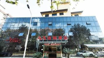 A modern building with a glass facade, a storefront with signage, and a street lamp in front.