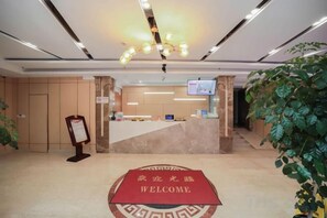 A hotel reception area with a reception desk, a digital screen, and a welcome mat. - A&A Chain Hotel (Chuansha East Huaxia Road Subway Station) (Shanghai)