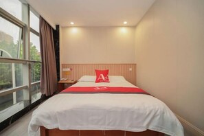 A hotel room with a bed, a nightstand, a window, and a view of the outdoors.