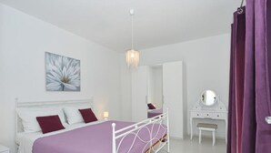 Une chambre à coucher avec un lit, une commode, un miroir et un tableau accroché au mur.