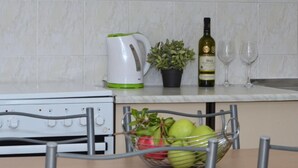 A kitchen with a white kettle, a bottle of wine, and two glasses on the counter.