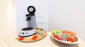 En kaffebryggare, två glas, en skål med snacks och en tallrik med något rött på ett bord.