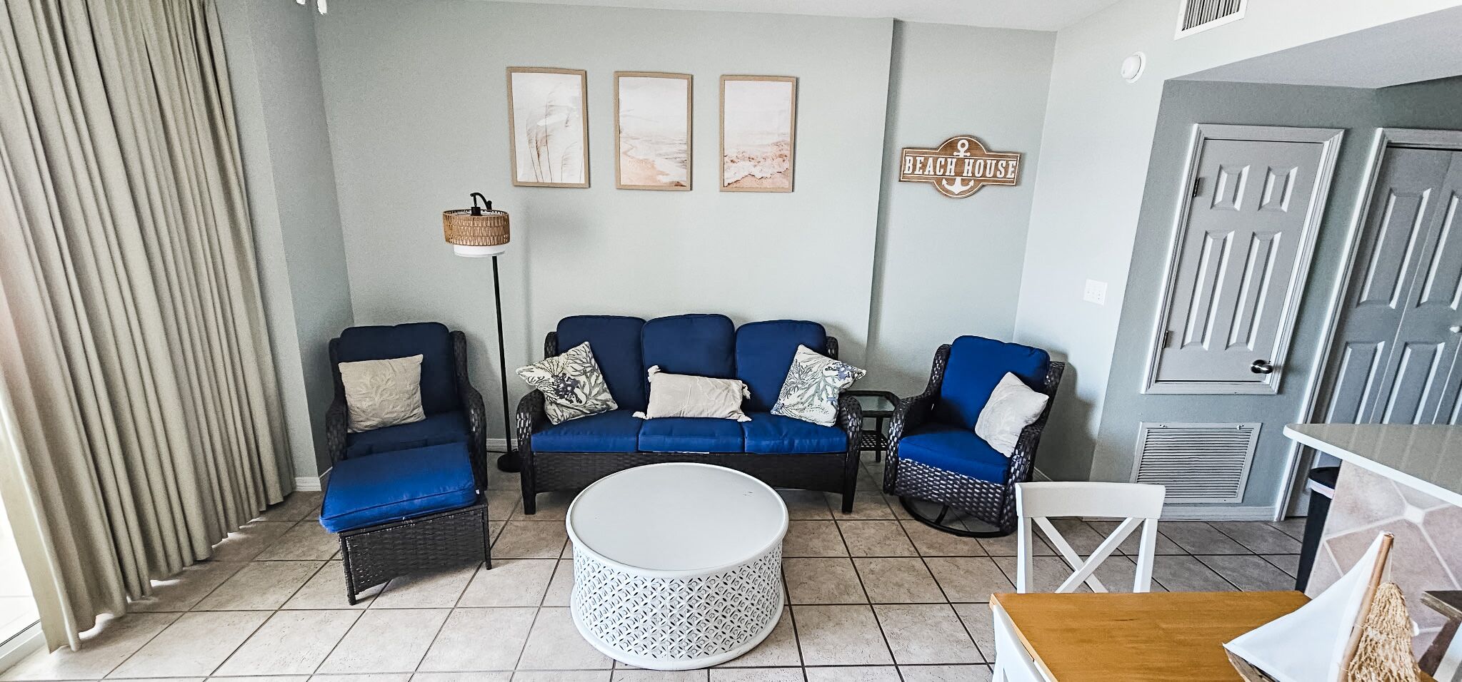 A living room with a blue sofa set, a round coffee table, and a wicker chair.
