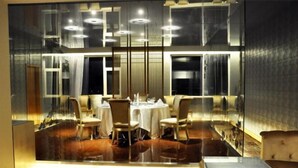 A modern dining area with a glass partition, round tables, and chairs. - Solar Valley Micro-E International Hotel (Dezhou)