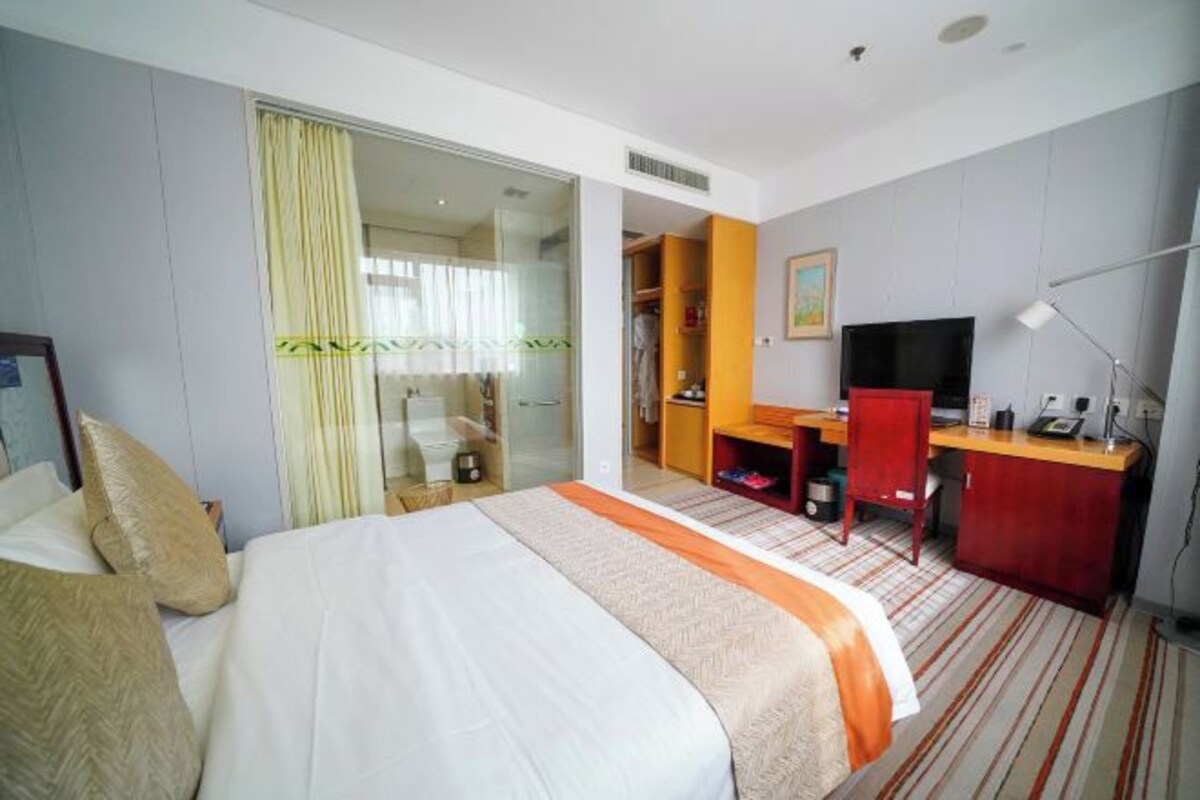 A hotel room with a bed, a desk, a TV, and a wardrobe.