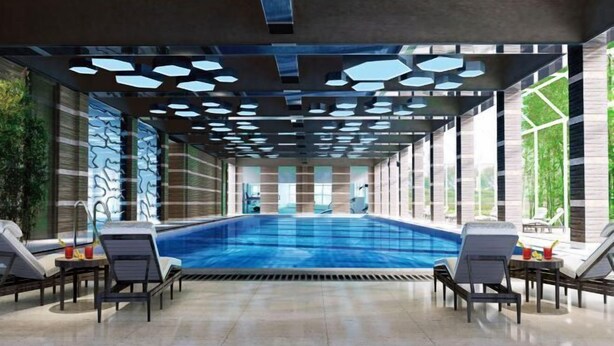 An indoor swimming pool with a modern design, featuring geometric ceiling panels and lounge chairs around the perimeter. - Solar Valley Micro-E International Hotel (Dezhou)
