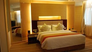 A hotel room with a large bed, a bedside table with a lamp, and a mirror reflecting the room. - Solar Valley Micro-E International Hotel (Dezhou)