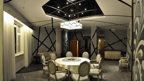 A dining area with a round table and chairs, a modern chandelier, and geometric wall patterns. - Solar Valley Micro-E International Hotel (Dezhou)