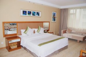 A hotel room with a large bed, a sofa, a nightstand, and a wall-mounted TV. - Solar Valley Micro-E International Hotel (Dezhou)