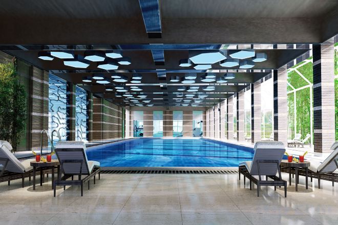 A swimming pool with lounge chairs, a tiled floor, and a ceiling with geometric patterns.