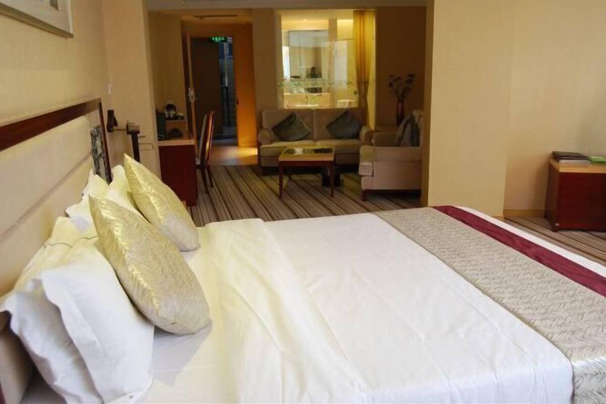 A hotel room with a large bed, a sofa, a coffee table, and a desk.